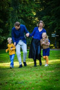 Vader en moeder lopen met de kinderen op het grasveld in Sonsbeek park in Arnhem.