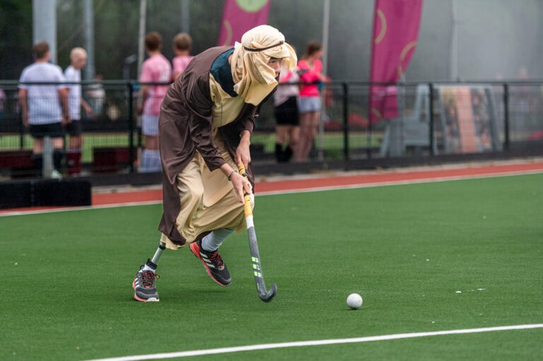 Hockeyspeler met onderbeen prothese speelt verkleed als herder een wedstrijd.